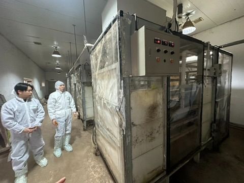 Researchers inspecting large-scale respiration chamber equipment for methane measurement